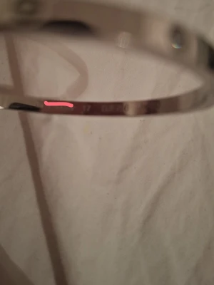 Silverfärgat stelt armband - Snyggt stelt armband i silverfärg med minimalistisk design. Armbandet är slätt och har en oval form, perfekt för att ge en stilren touch till din outfit. Materialet ser ut att vara metall och armbandet har en enkel låsmekanism.