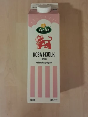 Arla rosa mjölk med jordgubbssmak - En 1-liters förpackning rosa mjölkdryck från Arla med smak av jordgubb. Kartongen är vit och rosa med illustration av en rosa ko och jordgubbar. Perfekt till frukost eller som bas i rosa mannagrynsgröt. HELT OÖPPNAD! KÖPTE IDAG