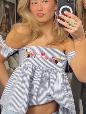Randig offshoulder blus med broderi - Superfin offshoulder blus med blåvita ränder och broderade blommor framtill. Luftig modell med volang och korta puffärmar. Perfekt för en trendig och somrig look.