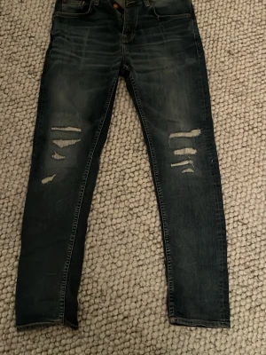 Nudie Jeans Steady Eddie II  - Säljer dessa riktigt snygga Nudie Jeans I modellen Steady Eddie II, de har väldigt feta slitningar och schyssta honeycombs.   Vid frågor eller funderingar hör av er!   Skickar snabbt 🚚  Svarar snabbt ✅   📏  Midja 43 cm Längd 108 cm  Lårbredd 30cm Benöppning 17cm 