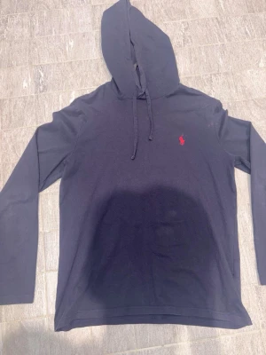 Ralph lauren hoodie - Saljer en stilren mörkbla hoodie fran Ralph Lauren med det klassiska röda logotypbroderiet på bröstet. Tröjan har en bekväm huva med dragsko och långa ärmar. Perfekt för en avslappnad look. Har nagra fläckar som kan ses på bilderna. Pris är diskuterbart.