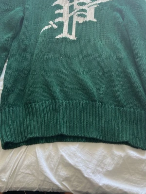 Grön sällsynt stickad tröja Polo Ralph lauren - Mörkgrön stickad tröja från  Ralph lauren 5th Ave med vitt grafiskt mönster på framsidan. Tröjan har ribbstickade muddar vid ärmslut och nederkant. Perfekt för dig som gillar klassisk och stilren design. Är perfekt för dig som är runt 185!