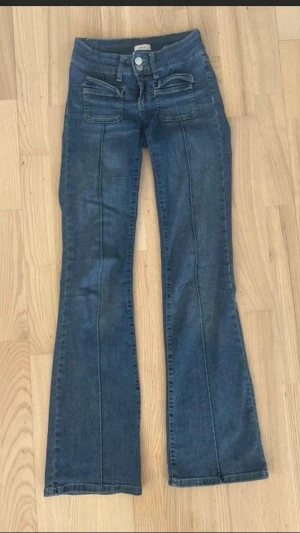 Blå utsvängda jeans från Nelly - Snygga blå jeans från Nelly med utsvängda ben och markerade sömmar framtill. Jeansen har dubbla knappar i midjan och två stora fickor framtill. I storlek 32(Xxs) men kan passa 34(Xs)💗!!!