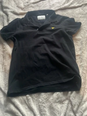 Lyle and Scott pikétröja svart - Säljer nu min svarta pikétröja från Lyle and Scott. Har använt den några fåtal gången och skulle starkt rekommendera den inför sommaren. Den skulle passa bra på personen som är runt 1,75. Hör av er för mer inf.