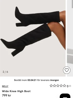 Svarta knähöga boots från Nelly - Stilrena svarta knähöga boots från Nelly med bred passform vid knäet. Skorna har en hög, kraftig klack och spetsig tå. Tillverkade i ett slätt material som ger en trendig look. Perfekta för att lyfta vilken outfit som helst.