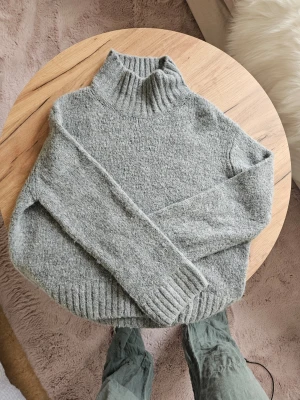 Grå stickad polotröja - Mysig grå stickad polotröja med bred ribbstickad krage, ärmslut och nederkant. Tröjan har en avslappnad passform och är perfekt för lager-på-lager. Materialet känns mjukt och värmande, perfekt för kyliga dagar.☺️