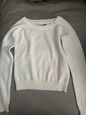 Vit stickad tröja från FB Sister - Klassisk vit stickad tröja från FB Sister med rund halsringning och ribbade muddar vid ärmslut och nederkant. Tröjan har en enkel och stilren design som passar perfekt till många olika outfits. de är en liten fläck på tröjan som syns på sista bilden kan kanske gå bort annars är den använd fåtal gånger 💞