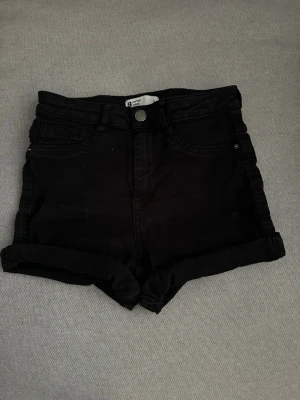 Svarta highwaist jeans shorts Gina Tricot - Svarta highwaist shorts från Gina Tricot med klassisk femficksdesign och uppvikta benslut. 
