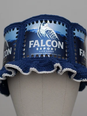 Virkad ölhatt Falcon - Unik virkad ölhatt med Falcon.  Virkad i 100% bomull. Passar upp till ca 61cm.  Vissa burkar kan ha mindre repor eller bucklor, vilket tyvärr kan uppstå under tillverkningen av hattarna. Insidan av burkarna slipas efter hålen tagits för att undvika vassa kanter. Därför kan det ibland finnas lite slipmärken, men det är inget som stör eftersom det är på insidan av hattarna.  Färger kan variera något beroende på skärminställningar.