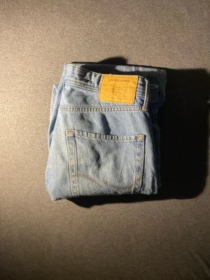 Ljusblå jeans från Jack & Jones - Snygga ljusblå jeans från Jack & Jones i klassisk rak modell. Jeansen har fem fickor, gylf med dragkedja och en läderpatch med logga bak i midjan. Perfekta för en avslappnad och trendig stil.