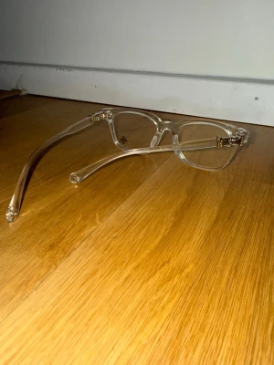 Transparenta chromehearts glasögon - Snygga solglasögon med transparent båge och fyrkantig form. Glasögonen har gulddetaljer vid gångjärnen som ger en cool touch. Perfekta för dig som vill ha en stilren och modern accessoar till din outfit.