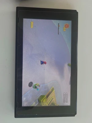 Nintendo Switch  - Nintendo Switch spelkonsol i svart med stor skärm och klassisk design. Konsolen har en rektangulär form och är tillverkad i plast. Perfekt för gaming både hemma och på språng. Märkets logga syns tydligt på baksidan.