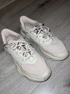 Beige Adidas Ozweego sneakers - Strumpliknande passform. Knyts med snören. Ovandel i stickat material och syntetläder med överdrag i TPU. Mjukt, åtsittande och lätt material. Textilfoder EVA-mellansula med dämpande Adiprene och Adiprene+. Gummiyttersula. Väl omhändertagna