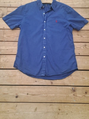 Blå kortärmad skjorta från Ralph Lauren S - Snygg blå skjorta från Ralph Lauren i slim fit-modell. Storleken är s. Bra för dig som vill ha bra skjorta till liten peng. Hör av er vid frågor. Fraktar inom 12 h.