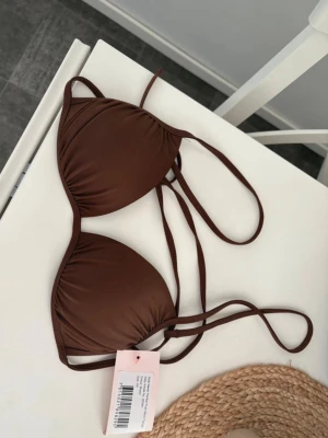 Brun trekantsbikini från Nelly - Snygg brun trekantsbikini från Nelly i modellen Perfect Push Bikini Triangle. Bikinin har tunna knytband och klassisk trekantsform, perfekt för stranddagar. Tillverkad i mjukt och stretchigt material för en bekväm passform. Den har push up, prislapp kvar helt ny