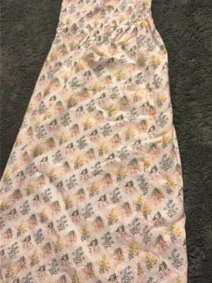 Blommig maxiklänning från H&M - Säljer en söt maxiklänning från H&M i storlek xs. Klänningen är vit med blommigt mönster i pastellfärger som rosa, gul och blå. Smockad upptill och med lång, luftig kjol. Perfekt för varma dagar och somriga vibes! Klänningen är helt ny med prislapp! 
