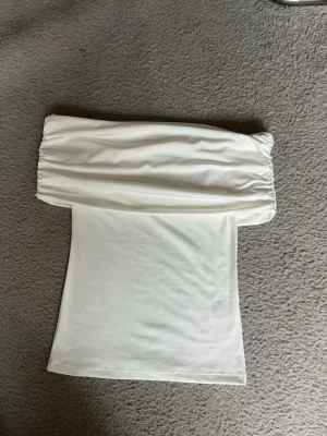 Vit offshoulder topp - TRYCK EJ KÖP DIREKT!!💗Snygg vit offshoulder topp med rynkad överdel och slät kropp. Perfekt för dig som vill ha en stilren och trendig look. Toppens axelbandslösa design ger en cool vibe och passar till många outfits. Hör av dig vid intresse💗