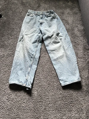 Ljusblåa baggy jeans - Säljer ett par ljusblåa baggy jeans med raka ben och hög midja. Jeansen har klassisk femficksdesign och är gjorda i denim. Perfekta för en avslappnad och trendig look.
