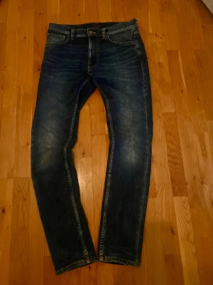 Nudie jeans lean dean  - Säljer ett par Nudie Jeans Lean Dean jeans i storlek W30 L32. Snygg passform med tapered fit och stretch för bra komfort. Jeans i mycket fint skick med snygga fades. Perfekta till både vardag och snyggare outfits.    Mått: - Midja: 43 cm   - Längd: 107 cm   - Lårbredd: 26 cm   - Benöppning: 16 cm    Skickas snabbt!