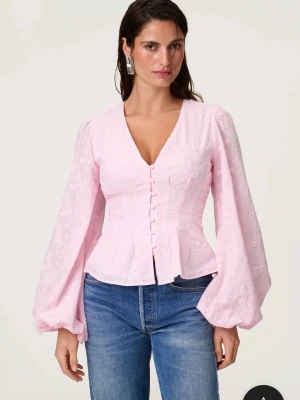 Ljusrosa blus med puffärmar - Supersöt ljusrosa blus med v-ringning och markerad midja. Blusen har långa puffärmar och knappar framtill. Tunt, broderat tyg med blommönster ger en romantisk vibe. Perfekt att styla med jeans eller kjol. Aldrig använd 