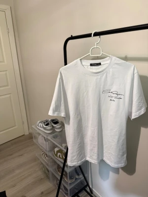  Cole Buxton T-shirt S - Säljer en stilren vit t-shirt från Cole Buxton med svart tryck fram och bak. T-shirten har rund hals och korta ärmar. Perfekt för dig som gillar minimalistisk design med en touch av streetwear.
