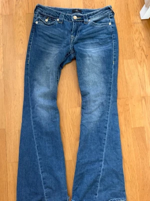 Blå True Religion Joey flare jeans - Säljer ett par blå True Religion Joey jeans med låg midja och utsvängda ben. Köpt för 1400kr ungefär. Priset kan diskuteras vid snabb affär’