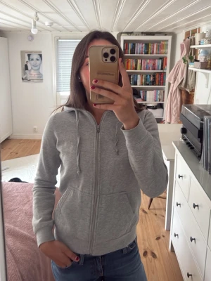 Ljusgrå zip hoodie med huva - Säljer en ljusgrå hoodie med dragkedja och huva. Tröjan har fickor framtill och justerbara snören i huvan. Perfekt för en avslappnad och chill stil. Passar till jeans eller mjukisbyxor.