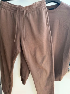 Brunt mjukisset från HM - Mjukisset från HM i bra skick. Byxorna är i storlek L och tröjan i storlek S men skulle säga att tröjan är lite större i modellen eftersom den är ”Relaxed fit”.