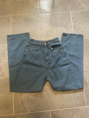 Blå raka jeans - Säljer ett par klassiska blå jeans och raka ben. Jeansen har fem fickor, bälteshällor och stängs med knapp och dragkedja. Materialet är slitstark denim i bomull. Perfekta för en avslappnad och trendig look.