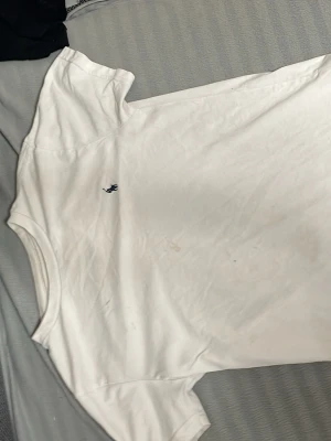 Vit t-shirt från Polo Ralph Lauren - Klassisk vit t-shirt från Polo Ralph Lauren med den ikoniska mörkblå loggan broderad på bröstet. T-shirten har rund halsringning och korta ärmar. Tillverkad i mjuk bomull som känns skön mot huden. Perfekt basplagg för alla tillfällen.