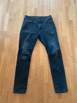 slim fit jeans med slitningar - Säljer dessa sköna slim fit jeans från nudie. I väldigt bra skick och är i storlek W28 L30. Jag på bilden är 180cm lång