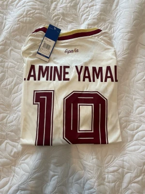 Spanien Lamine Yamal matchtröja - Spaniens bortaställ i VM med nummer 19 & LAMINE YAMAL på ryggen. Tröjan är i storlek L och kan fraktas omgående. 