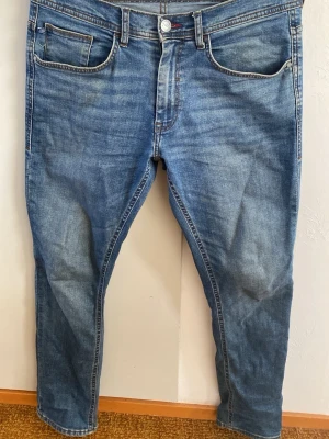 Blå slim fit jeans från Blend  - Snygga blå jeans i slim fit-modell med klassisk femficksdesign och dragkedjegylf. Jeansen har en lätt tvättad look och kontrastsömmar. Perfekta för en avslappnad och trendig stil. Materialet är bomullsdenim.