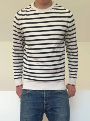 Vit Randig tröja - Vit randig stickad tröja från Tommy Hilfiger och är i strl M men passar även S! Bra skick utan nåra defekter och hör gärna av er vid frågor elr funderingar!!
