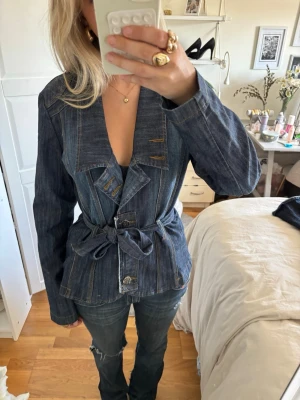 Vintage Mörkblå jeansjacka med knytskärp - Säljer denna Jättesnygga jeansjacka med snygga detaljer. jackan är endast använd en gång och har inga defekter, jättefin jacka till hösten bara att höra av sig vid frågor. Jackan är i storleken XL men passar som S också eftersom man kan knyta skärpet hur hårt man vill den ska sitta men den passar mig bra som vanligtvis har storlek s 💗💗