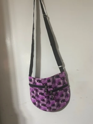  axelväska  - Väskan har justerbar svart axelrem och flera dragkedjefack både fram och bak. Materialet ser ut att vara syntetiskt tyg med glansig finish. Perfekt för dig som vill sticka ut med en färgglad accessoar. Helt ny , 89kr/st 