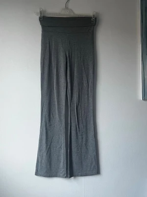 Grå ribbade bootcut leggings - Säljer ett par grå leggings med bootcut-modell och hög midja. De är ribbade och har en mjuk, stretchig känsla som gör dem riktigt bekväma. 