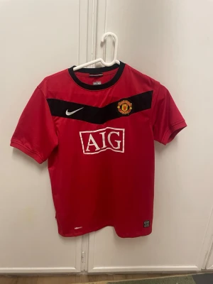 Manchester United Nike tröja XL röd - Säljer en röd Manchester United tröja från Nike i storlek XL. Tröjan har svart detalj över bröstet, klubbmärke och vit Nike-logga. AIG-logga på framsidan. Perfekt för dig som älskar fotboll och vill ha en klassisk supportertröja.