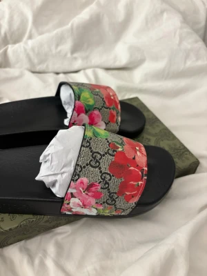 Gucci tofflor  -  Gucci tofflor med jättefint tryck på, aldrig använda för dom passade inte,