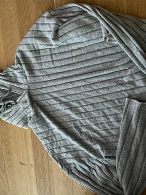 Grå ribbad hoodie från SHEIN - Mysig grå hoodie från SHEIN i ribbat material. Tröjan har långa ärmar och en avslappnad passform med huva. Perfekt för chill dagar eller när du vill ha något bekvämt och stilrent. Tillverkad i mjuk bomullsblandning.