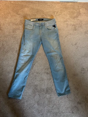 Ljusblå slim fit jeans från Replay  - Säljer ett par ljusblå slim fit jeans från Replay med klassisk femficksdesign och läderpatch bak i midjan. 30W 32L