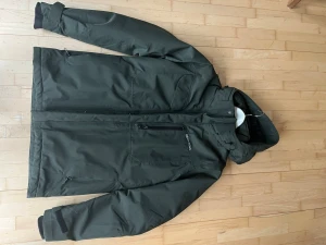 Mörkgrön parkas från Didriksons - Säljer en mörkgrön Didriksons skal-/regnjacka i storlek M. 100% vattentät och vindtät – perfekt för höst, vår och regniga dagar 🌧️ • Avtagbar/justerbar huva • Dragkedja + knäppning framtill • Fickor med dragkedja • Justerbara ärmslut • Lätt fodrad – fungerar både till vardag och promenader Jackan är i mycket fint skick, inga hål eller skador. Endast normalt, väldigt lätt använd. Nypris ca 1400–1800 kr. Rökfritt hem. Skickas snabbt