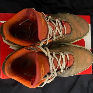 Lebron 21 queen conch - Säljer ett par unika Nike basketskor med orange och beige färgskala. Skorna har vita snören, orange innerfoder och detaljer samt en beige sula med svarta prickar. Swoosh-loggan syns på sidan och ovandelen har ett marmorerat mönster. Perfekta för dig som gillar sportig stil. Har inte original boxen 