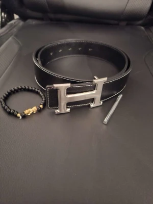 Svart bälte - Svart bälte med silvrigt spänne, hål görare och armband ingår, aldrig använd