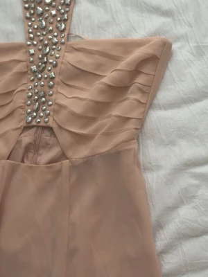 Rosa  halterneckklänning med pärlor - Denna klänning är köpt ur en collection på H&M för några år sen och går ej att köpa längre, den är superfin och man knyter banden runt halsen som en halterneck klänning! 🥰💞  ⚠️pris kan diskuteras⚠️ Den är använd 1 gång!
