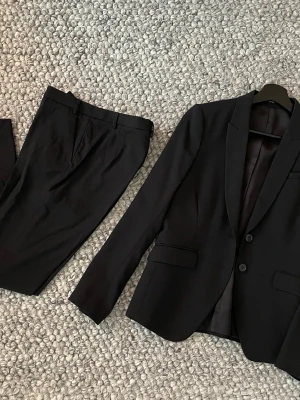 Tiger of Sweden kavaj & byxa - Tiger of Sweden kavaj & byxa i perfekt skick. Använt vid ett tillfälle.                                         Kavaj modell Ruma i storlek: 34                          Byxa modell Lovann i storlek: 38                         Färg: svart