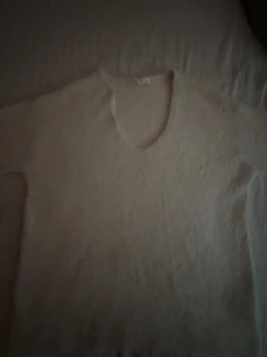 Beige stickad tröja med rund hals - Mysig beige stickad tröja med rund hals och långa ärmar. Tröjan har en enkel och klassisk design, perfekt för att hålla sig varm under kyliga dagar. Materialet ser ut att vara mjukt och fluffigt, vilket ger en skön känsla.