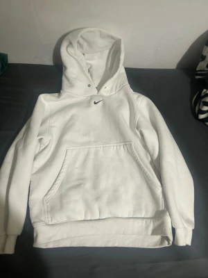 Vit Nike hoodie - Säljer en klassisk vit hoodie från Nike med liten svart logga på bröstet. Hoodien har börjat bli liten på mig så därför säljer jag den.