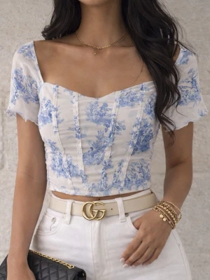 Blåvit blommig topp - Trendig blåvit topp med blommigt mönster och croppad passform. Toppen har korta ärmar, hals och markerade sömmar framtill för en snygg siluett. Perfekt att styla med höga jeans och accessoarer.