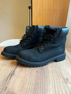 Svarta Timberland kängor i mocka - Svarta Timberland boots med svart snörning.  Storlek 39. Använd enstaka gång  Har små synligheter på användning men i superfint skick, lite dammiga då dom stått ett tag☺️